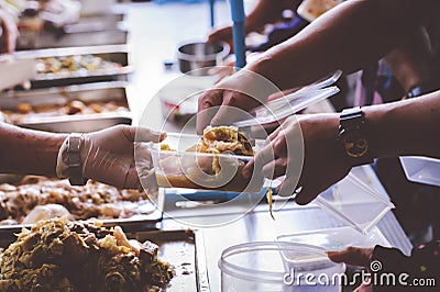 Providing free food to the poor : The hands of beggars receive donated food Stock Photo