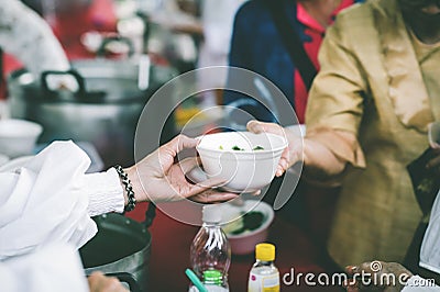 Providing free food to the poor : The hands of beggars receive donated food Stock Photo