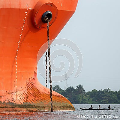 Prow of a big ship face to face with a small wooden pirogue Editorial Stock Photo