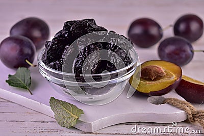 Prune in a glass bowl and fresh plums.Close-up. Stock Photo