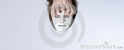 Psychedelic surrealistic concept. Lost thoughts. The head in a white mask without a body is held by crooked fingers. Template for Stock Photo