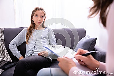 Psychiatrist With Clipboard Sitting Near Girl Stock Photo