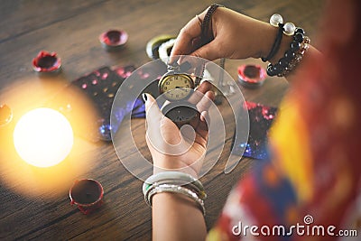 Psychic readings and clairvoyance concept - Crystal ball fortune teller with hands hold retro pocket watch and Tarot cards reading Stock Photo