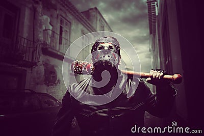 Psycho man in hockey mask with bloody baseball bat Stock Photo