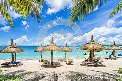 Public beach with lounge chairs and umbrellas, Mauritius island, Africa Stock Photo