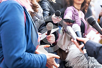 Public figure talking to the media, journalists holding microphones at news conference Stock Photo