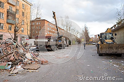 Public service workers put demolition waste of old pavilions in a truck with a crane in an alley near a residential building Editorial Stock Photo