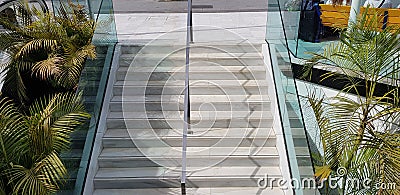 Public staircase stairway and chrome metal handrail divider with safety glass side sections Stock Photo