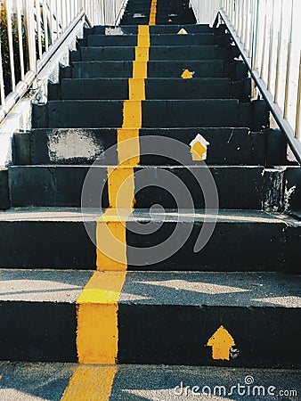 Public staircase with yellow lines to divide the way up and the way down / Signs of the way to up stairs but have no signs to way Stock Photo