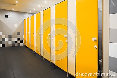 Public toilet interior with bright yellow stalls Stock Photo