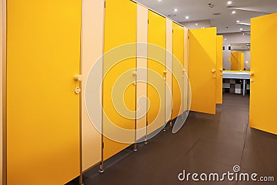 Public toilet interior with bright yellow stalls Stock Photo