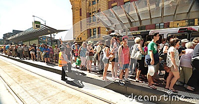 public transport commuters enter thr trams aided by customer service representatives. Editorial Stock Photo
