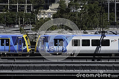 Two yellow-blue metro trains run side by side on the many tracks in Melbourne, Australia Editorial Stock Photo