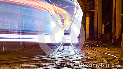 Public transportation in a city. Tram leaving the station, traffic lights, people, street, houses, overhead wires, rails. Movement Stock Photo