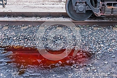 A puddle of red potash fertilizers after rain on crushed stones near the railway tracks on industrial plant Stock Photo