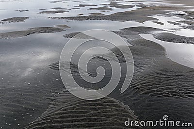 Puddles and undulations in the sand caused by the outgoing tide Stock Photo