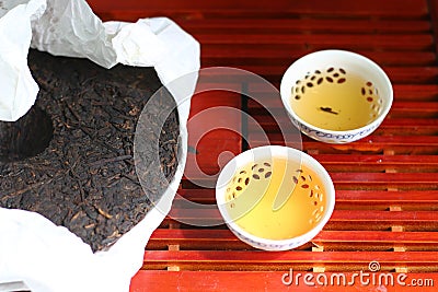 Puer tea. Packed pancake of traditional chinese puer tea with white teaput. Asian pressed pu-erh tea and crockery tea set, clay Stock Photo