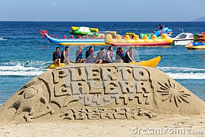 Puerto Galera - April 4, 2017: Sand castle with sign `Puerto Galera` on White beach with tourists and water activities on backgrou Editorial Stock Photo