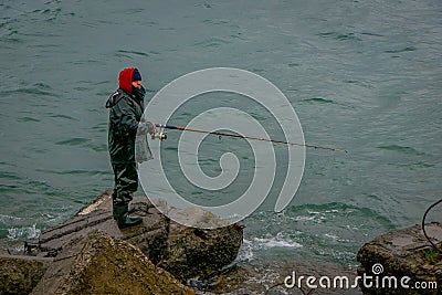 PUERTO VARAS, CHILE, SEPTEMBER, 23, 2018: Unidentified fisherman standing in a rock with a fishing rod on chilean Editorial Stock Photo