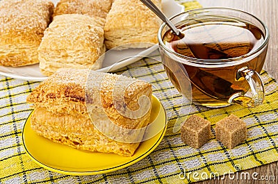 Puff cookies in dish, cup of tea, cookie in saucer on napkin on wooden table Stock Photo