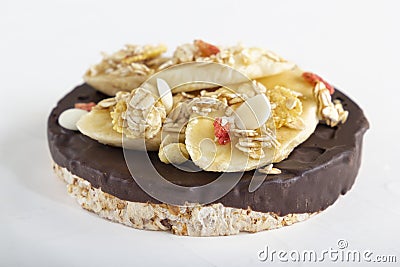 Puffed exploded wheat grains with chocolate glaze with muesli and cut banana slices on a light wooden background. Stock Photo