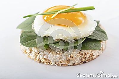 Puffed exploded wheat grains with fried egg and spinach leaves on a light wooden background. Stock Photo