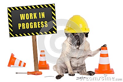 Pug dog with constructor safety helmet and yellow and black work in progress sign on wooden pole Stock Photo