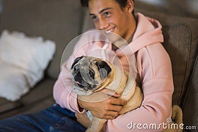 Pug and teenager together hugged on the sofa - pet and domestic dog at home Stock Photo