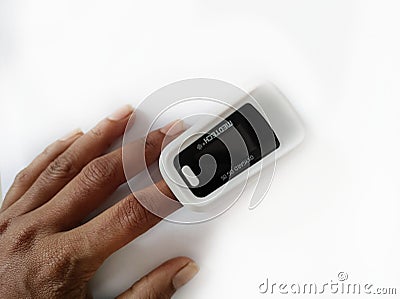 Pulse oximeter on white background. Close up of Finger and hand in an Oximeter Device. Editorial Stock Photo