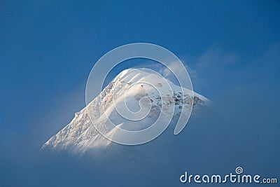 Pumori mountain peak is visible through thin fog in Himalayas Stock Photo
