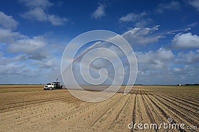 Pump truck irrigating fields near Homestead, Florida creating rainbow in spray. Stock Photo