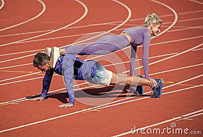 pumping up muscles. athletic man and woman in stand plank. male and female coach on stadium arena. healthy lifestyle Stock Photo