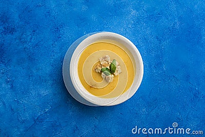 Pumpkin and carrot soup with cream and spinach with crackers on a classic blue background Stock Photo