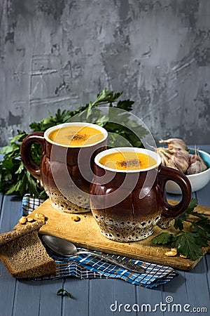 Pumpkin cream soup in mugs on gray blue background Stock Photo