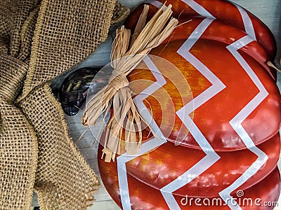 Pumpkin decorated with straw bow. Rolled up burlap tape. Halloween decor. Autumn, thanksgiving, holidays. Close-up. Stock Photo