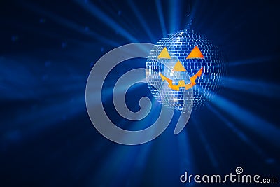 pumpkin disco ball at Halloween party, jack o'lantern with shiny rays in smoke Stock Photo