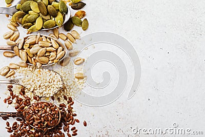 Pumpkin, flax, sesame and sunflower seeds in metal spoons on the left side of the table with copy space Stock Photo