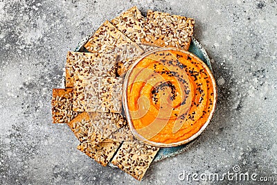 Pumpkin hummus seasoned with olive oil and black sesame seeds with whole grain crackers. Healthy vegetarian appetizer or snack. Stock Photo