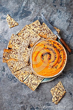 Pumpkin hummus seasoned with olive oil and black sesame seeds with whole grain crackers. Healthy vegetarian appetizer or snack. Stock Photo