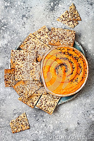 Pumpkin hummus seasoned with olive oil and black sesame seeds with whole grain crackers. Healthy vegetarian appetizer or snack. Stock Photo