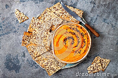 Pumpkin hummus seasoned with olive oil and black sesame seeds with whole grain crackers. Healthy vegetarian appetizer or snack. Stock Photo
