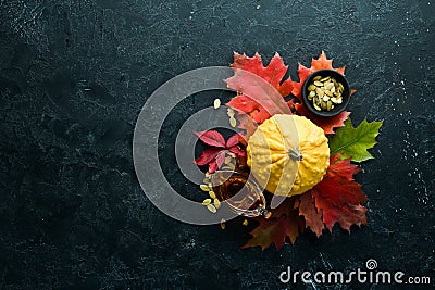 Pumpkin oil and pumpkins. Autumn vegetables. flat lay. On a black stone background. Top view. Stock Photo