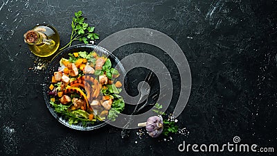 Pumpkin salad with chicken meat and vegetables in a black plate on a black background. Top view. Stock Photo