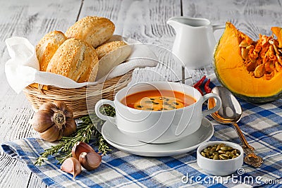 Pumpkin soup in a bowl with fresh pumpkins, garlic and parsley h Stock Photo