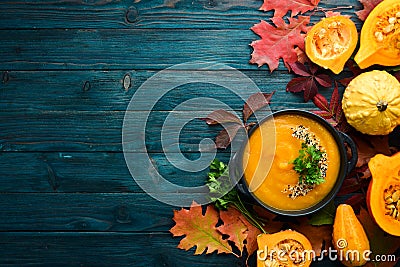 Pumpkin soup with pumpkin and colored autumn leaves. flat lay. On a blue wooden background. Top view. Stock Photo