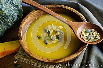 Pumpkin soup in a wooden bowl with fresh pumpkins Stock Photo