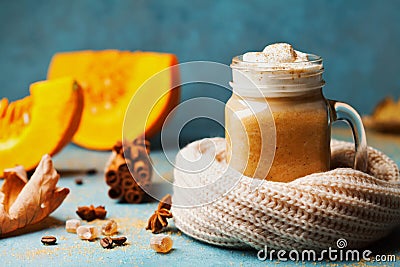 Pumpkin spiced latte or coffee in glass decorated knitted scarf on turquoise vintage background. Autumn, fall or winter hot drink. Stock Photo