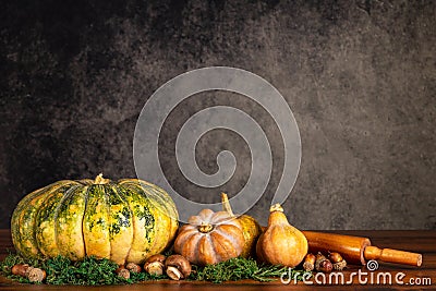 Pumpkins, butternut squash and mushrooms with rolling pin on a table over a vintage background with copy space Stock Photo