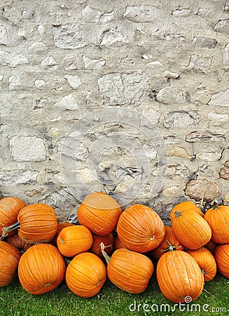 Pumpkins piled against a rustic stone wall Stock Photo