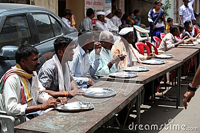 Pune, India - July 11, 2015: Indian pilgrims sitting on table on Editorial Stock Photo